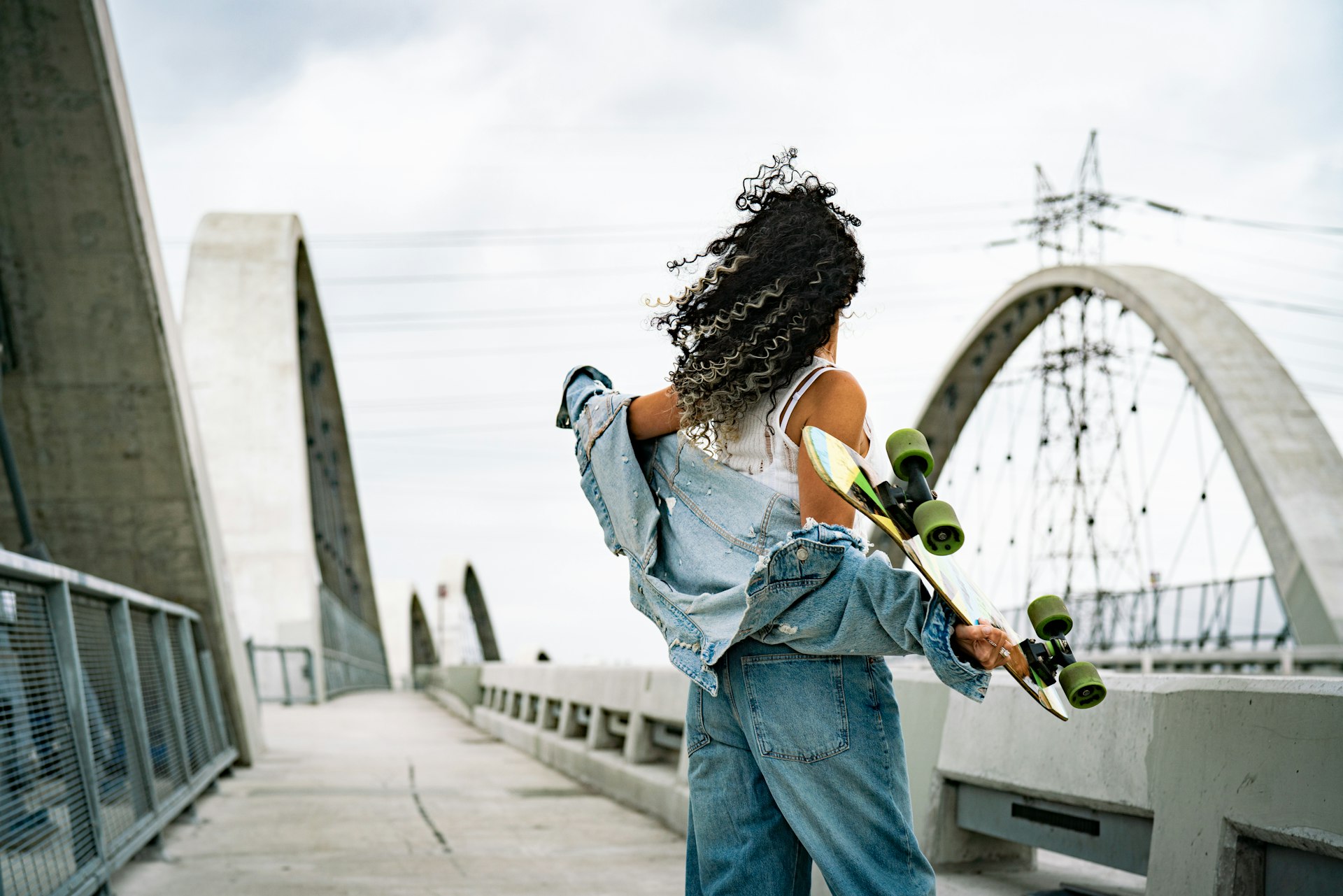 A woman holding a skateboard on a bridge